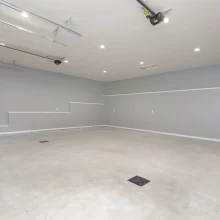 Spacious finished garage interior with gray walls, recessed ceiling lights, concrete floor, and overhead garage door tracks