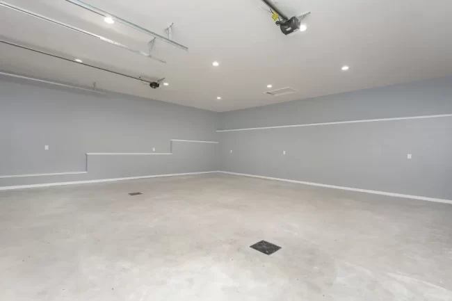 Spacious Finished Garage Interior | Pennings & Sons Spacious finished garage interior with gray walls, recessed ceiling lights, concrete floor, and overhead garage door tracks
