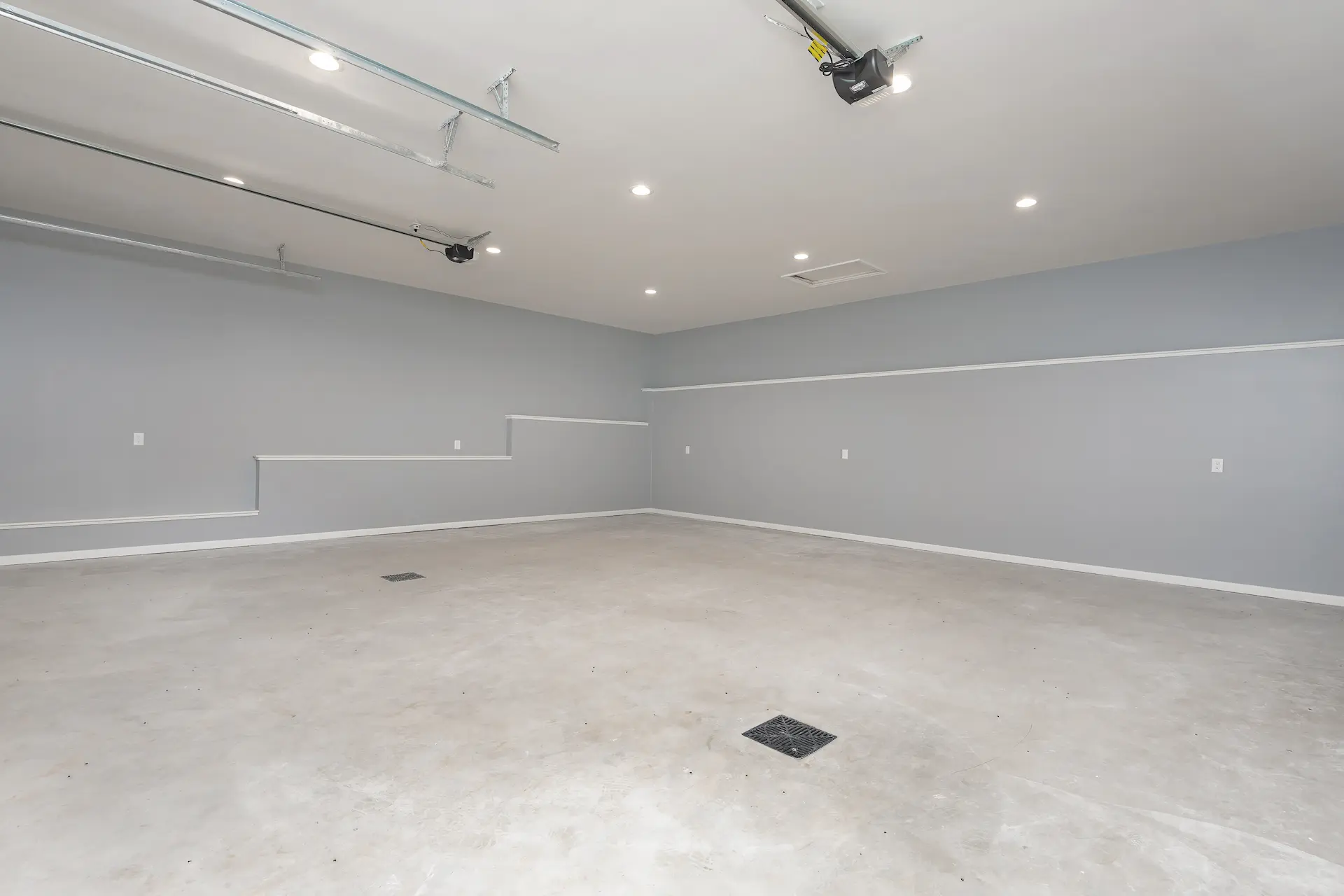 Spacious finished garage interior with gray walls, recessed ceiling lights, concrete floor, and overhead garage door tracks