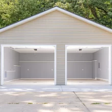 Finished rebuilt garage interior viewed from the driveway with open overhead doors, recessed lighting, gray walls, and white trim