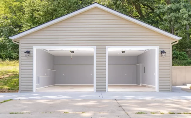 Finished Garage Interior from Driveway | Pennings & Sons Finished rebuilt garage interior viewed from the driveway with open overhead doors, recessed lighting, gray walls, and white trim