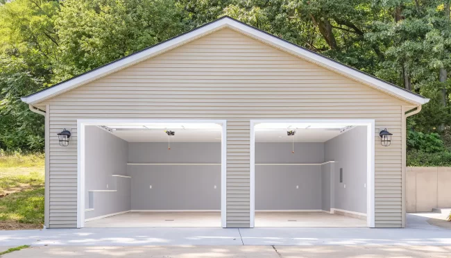 Finished Garage Interior from Driveway | Pennings & Sons Finished rebuilt garage interior viewed from the driveway with open overhead doors, recessed lighting, gray walls, and white trim