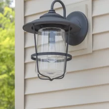 Close-up of a black exterior wall light installed on beige garage siding beside white trim
