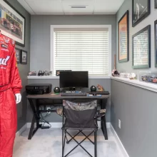 Small home office nook in the basement with sports memorabilia, desk, window, and display shelves.