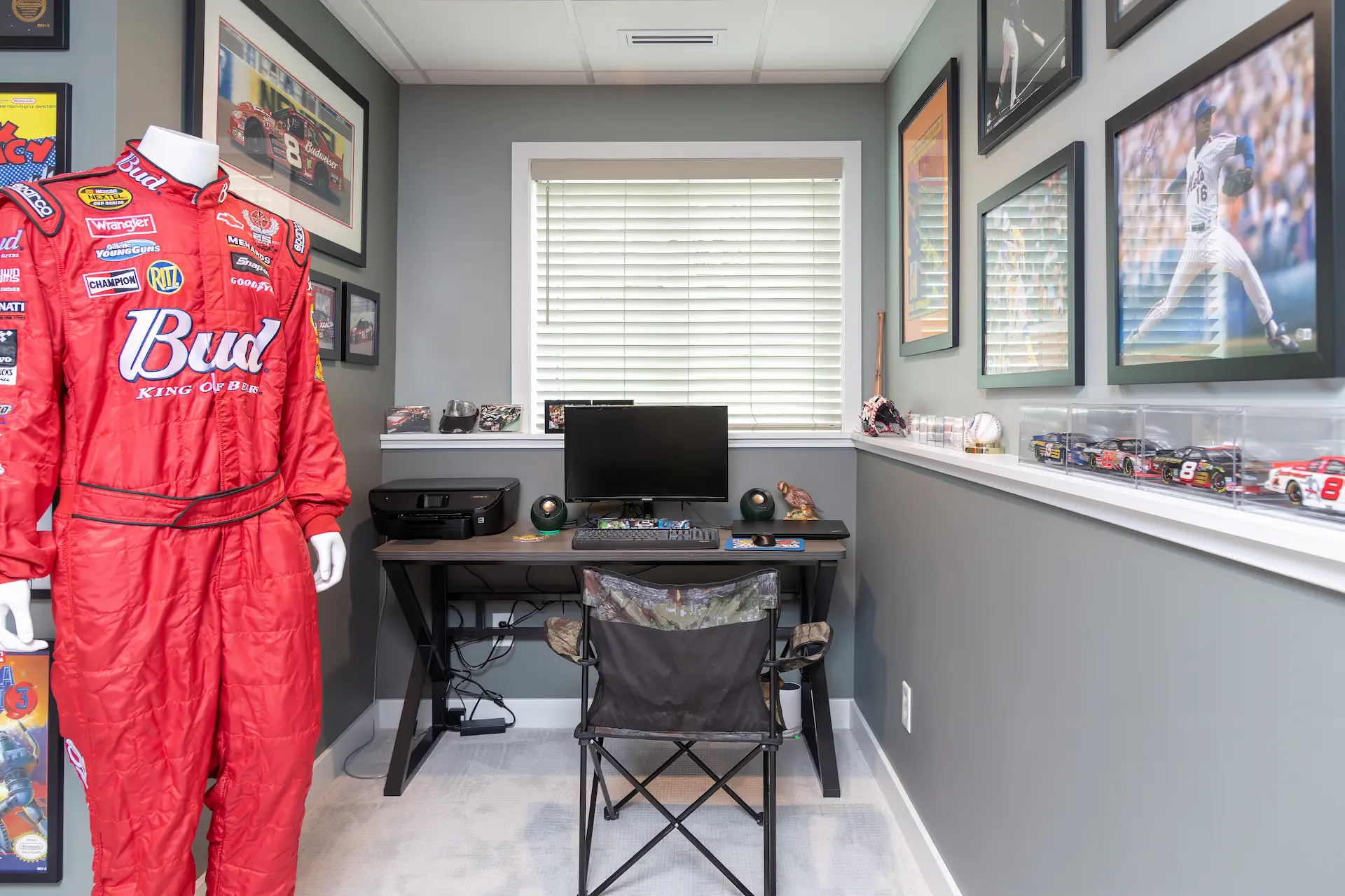 Small home office nook in the basement with sports memorabilia, desk, window, and display shelves.