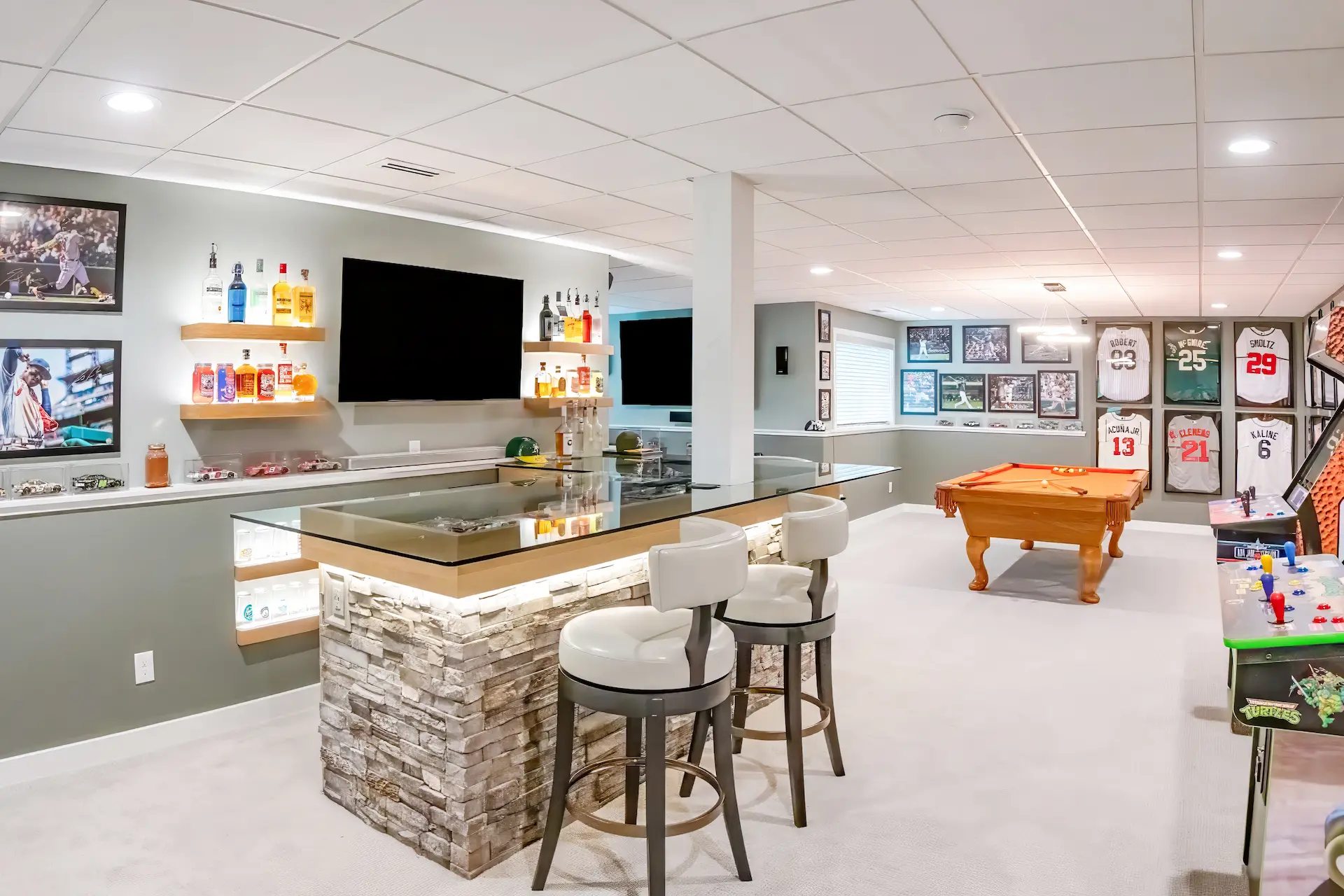 Finished basement rec room with a custom bar, pool table, sports memorabilia, and arcade games