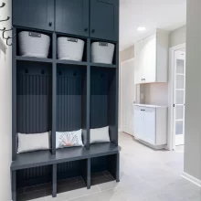 Custom mudroom lockers with dark blue finish, basket storage, beadboard backs, and built-in bench seating