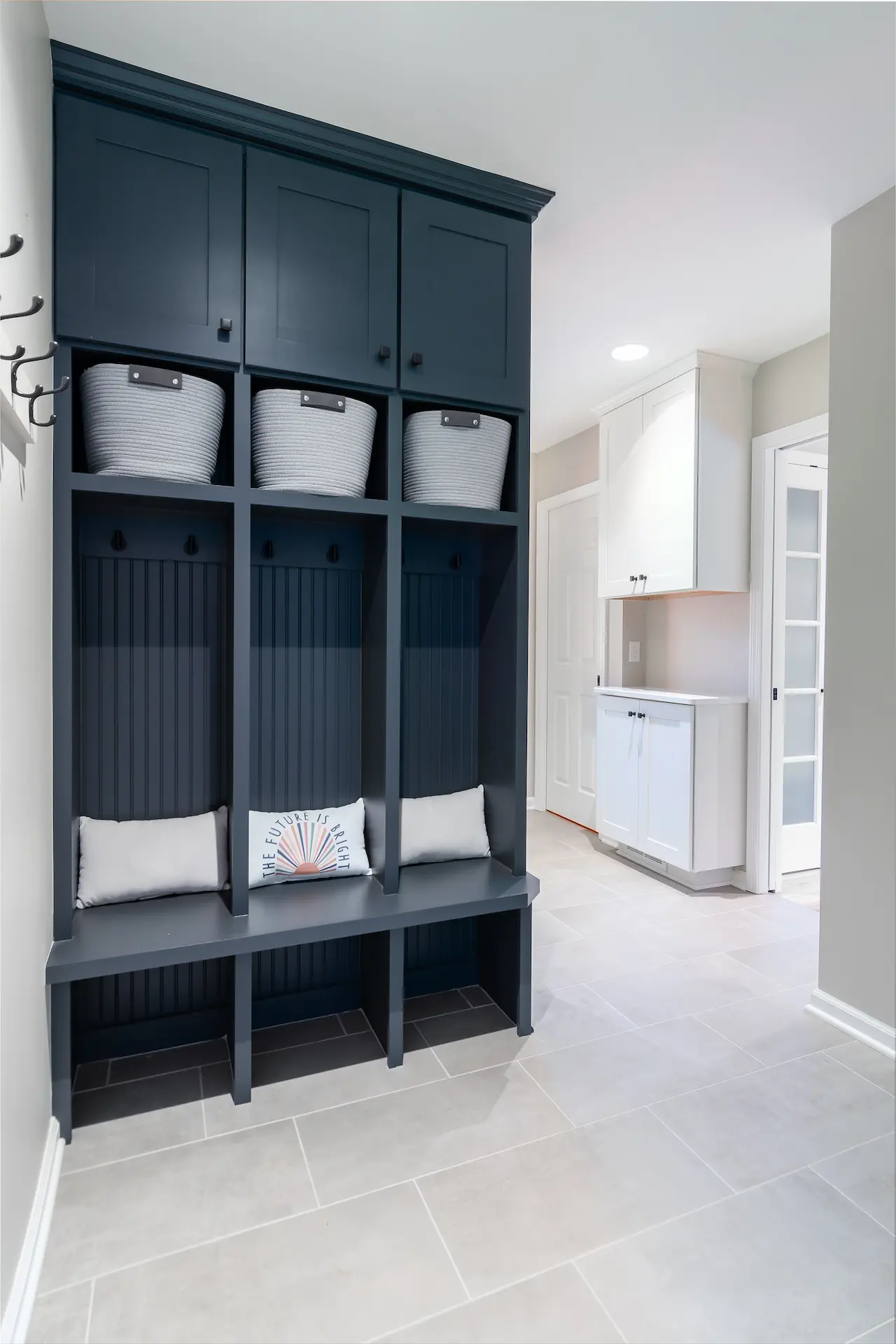 Custom mudroom lockers with dark blue finish, basket storage, beadboard backs, and built-in bench seating