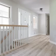 Updated entry hall with light wood flooring, white stair railing, and clean trim details