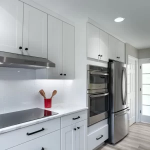 White shaker kitchen cabinetry with black hardware, stainless appliances, and a bright tile backsplash