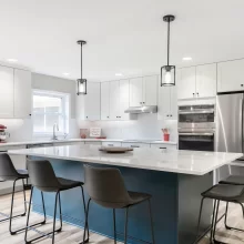 Large blue kitchen island with white countertop, bar seating, pendant lights, and updated cabinetry