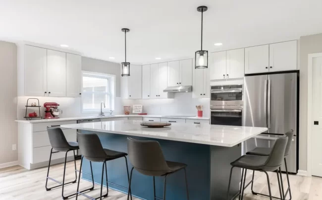 Blue Kitchen Island with Bar Seating | Pennings & Sons Large blue kitchen island with white countertop, bar seating, pendant lights, and updated cabinetry