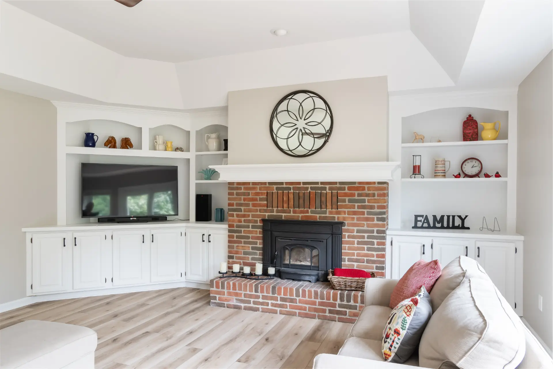 White built-in cabinetry and shelving surrounding a brick fireplace in a remodeled living room