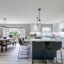 Open kitchen and dining area with blue island cabinetry, white cabinets, and light wood flooring