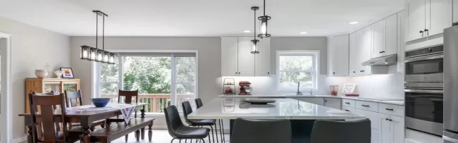 Open kitchen and dining area with blue island cabinetry, white cabinets, and light wood flooring