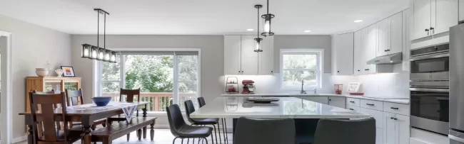 Open kitchen and dining area with blue island cabinetry, white cabinets, and light wood flooring