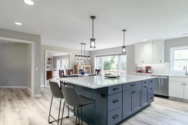 Bright remodeled kitchen with blue island, white cabinetry, dining area, and updated lighting