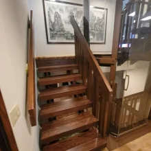 Finished wood stair treads next to a custom home elevator with glass panels and matching wood railings.